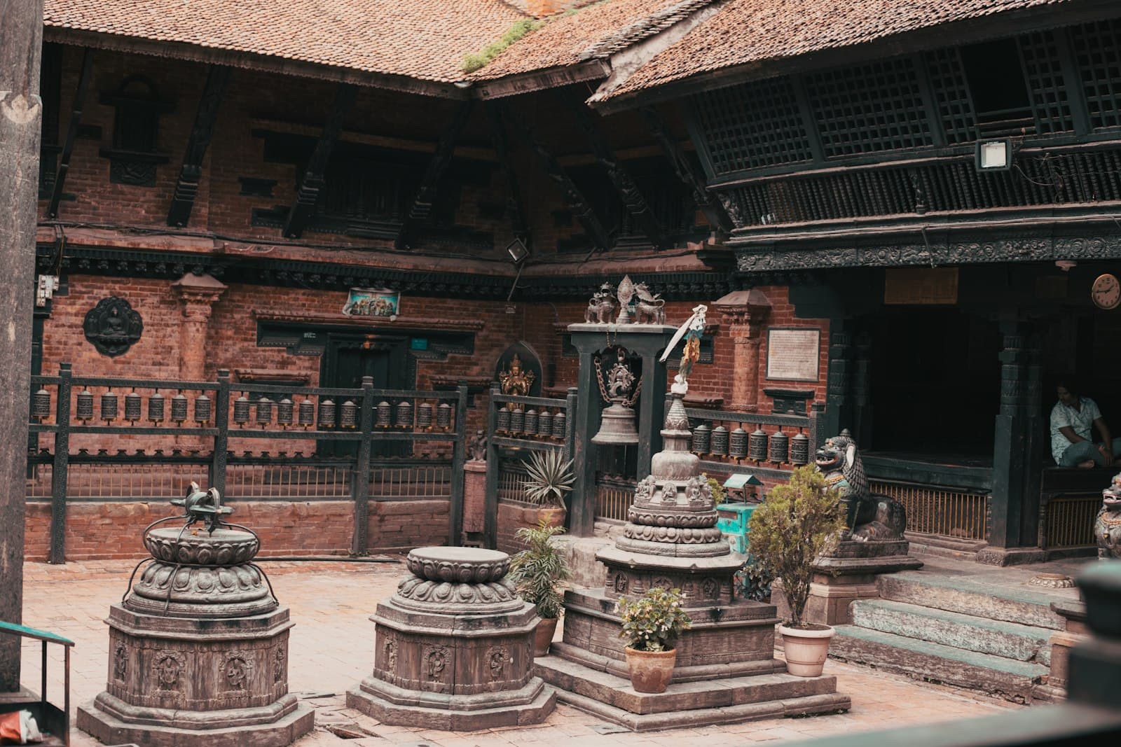 Stone stupas and carved wooden architecture in an ancient temple courtyard.